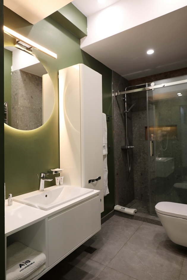 Amenajare baie minimalista, cu piatra de culoare neagra si un perete verde.