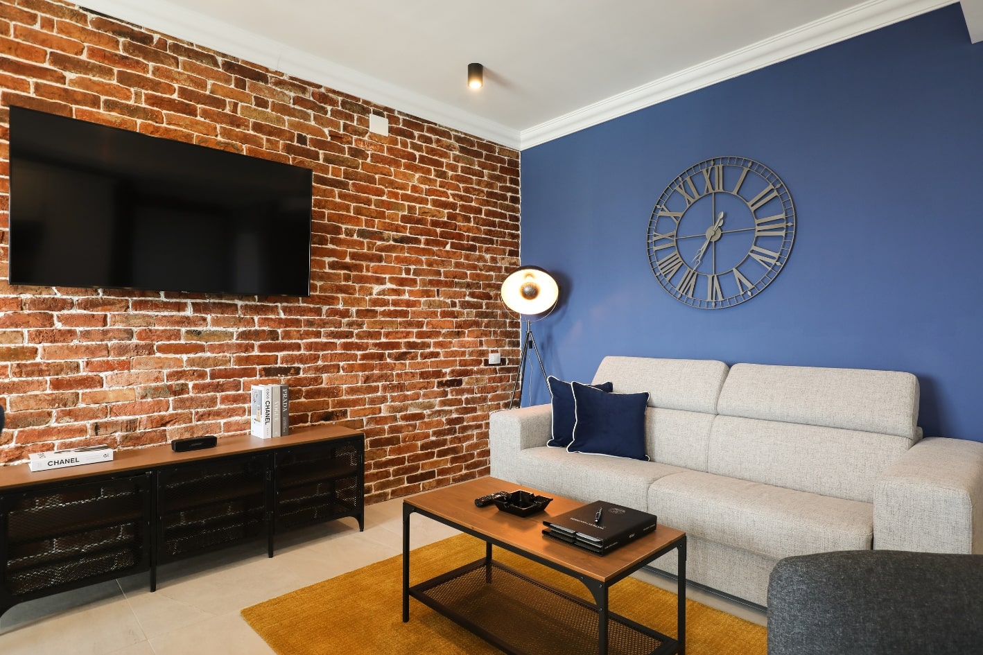 Apartament industrial cu un perete realizat din caramida aparenta si un alt perete de culoare albastra.