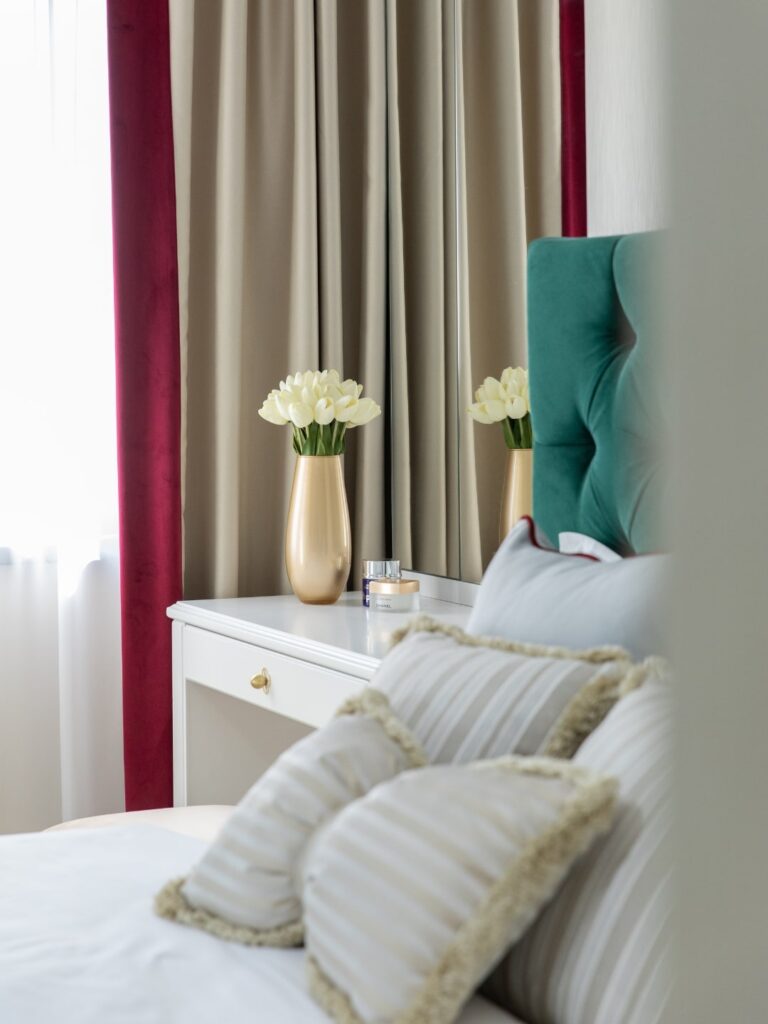 Dormitor ingust realizat in stil clasic cu diferite nuante de verde, alb si crem.