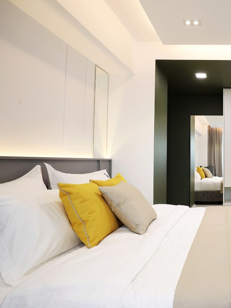 Design interior dormitor in stil minimalist, patul fiind imbracat in culori deschise, iar fundalul este alb.