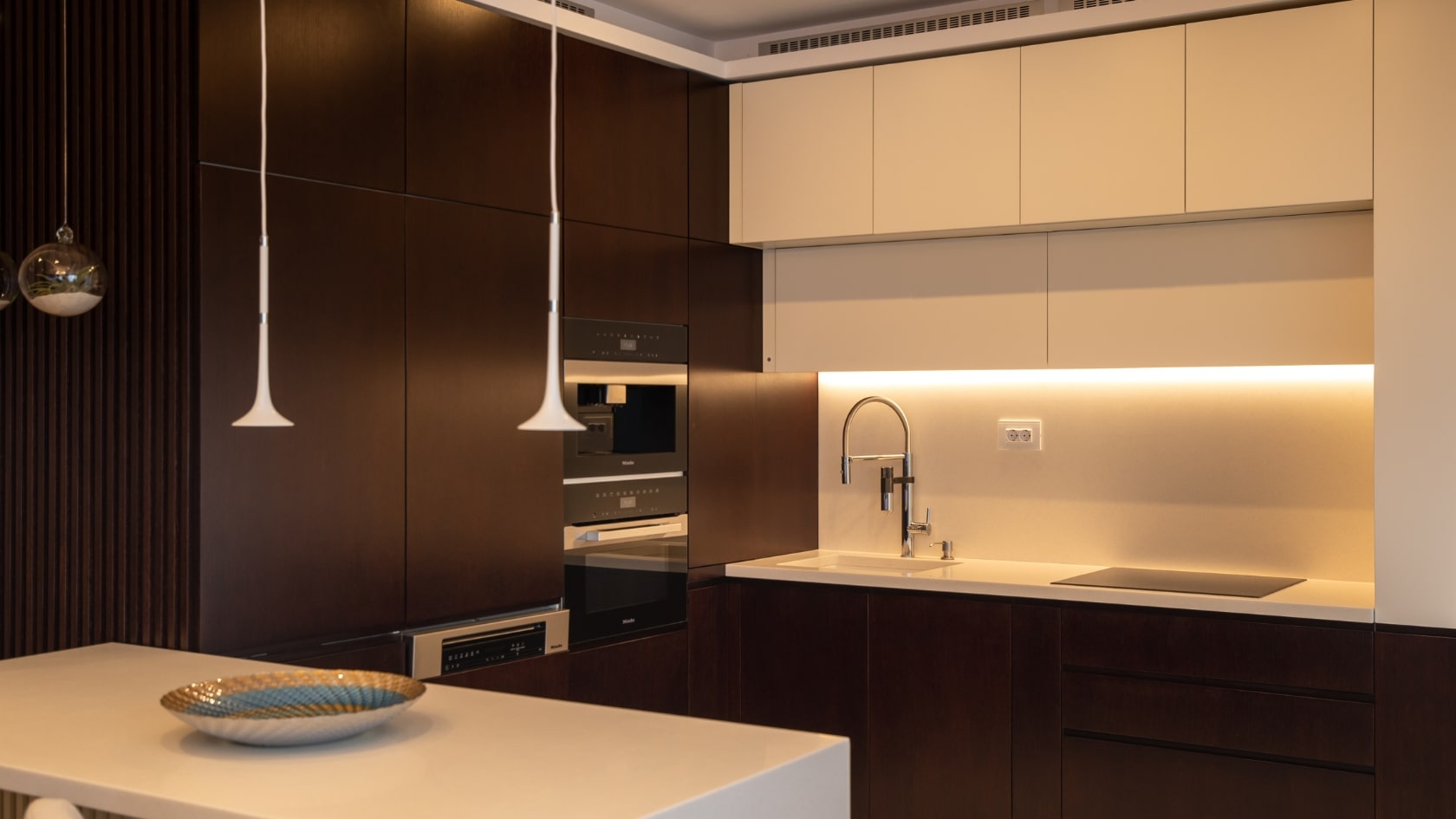 Amenajare interioara pentru o bucatarie moderna cu materiale de cea mai inalta calitate si cu o iluminare de accent cu banda LED deasupra blatului de lucru.